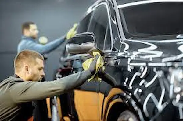 Car service technician applying ceramic car coating for advanced protection against scratches, enhancing vehicle surface durability and resilience